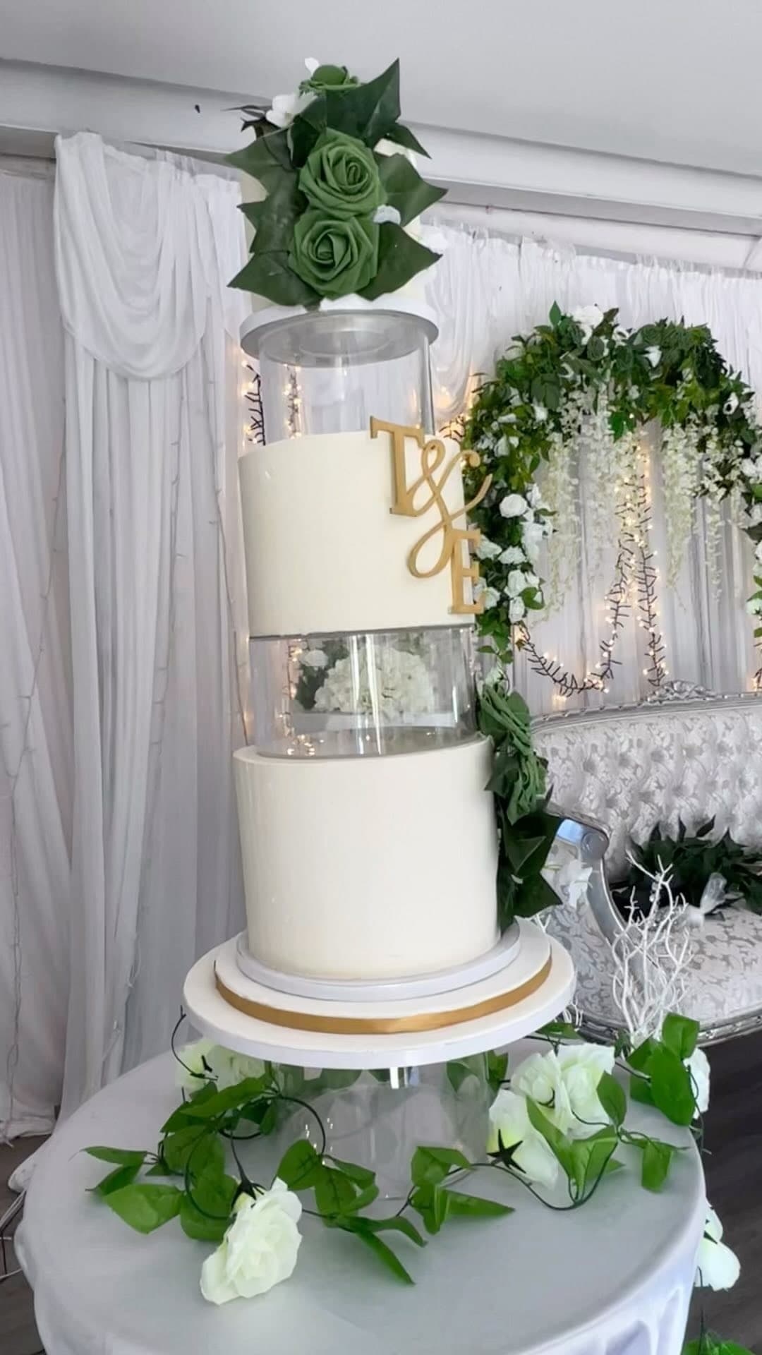 Tiered white wedding cake with greenery by MKCE Manchester